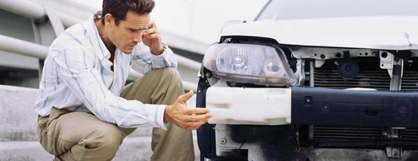 A driver examines damaged car, identifying potential damage exceeding typical wear and tear during a lease.