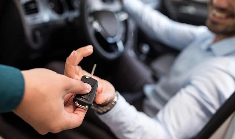 Seller handing car keys to smiling customer in car leasing transaction